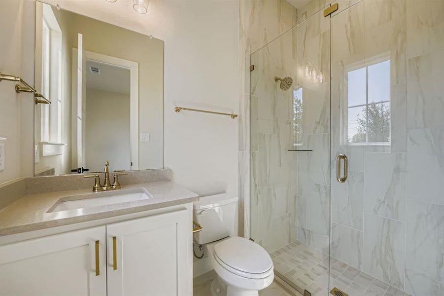 Bathroom featuring a marble finish shower and vanity