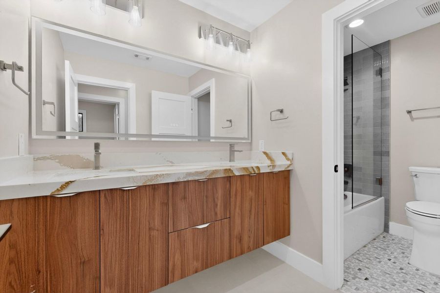 A well-appointed bathroom with a dual vanity featuring wood cabinetry and an elegant countertop.