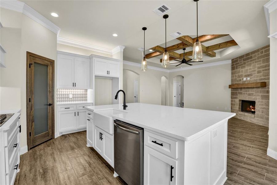 Kitchen with wood-type flooring, white cabinetry, coffered ceiling, beamed ceiling, and a center island with sink