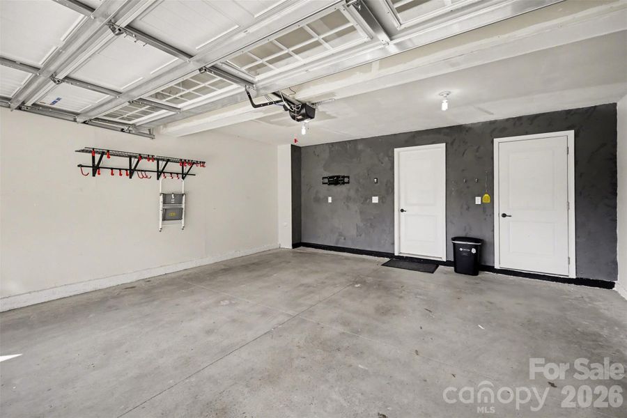 Spacious two-car garage featuring wall-mounted storage racks with interior access, and storage closet
