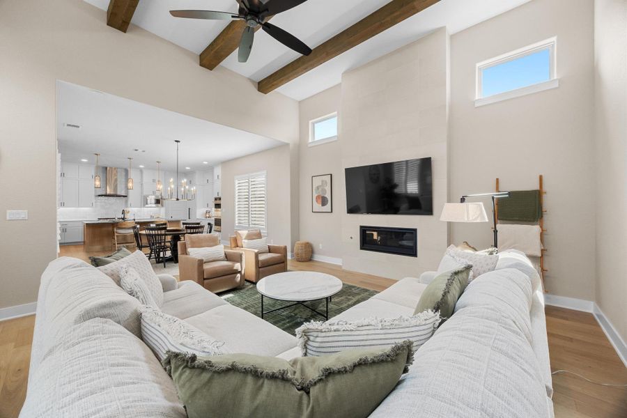 Living area with healthy amount of natural light, light wood-style flooring, a towering ceiling, beam ceiling, and a chandelier