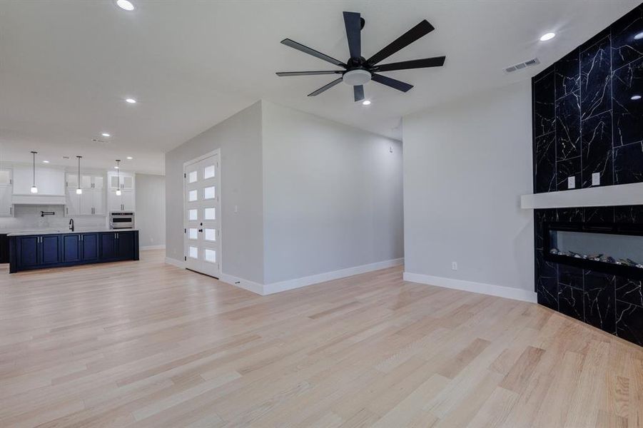 Open-concept living area featuring light wood-finish flooring, recessed lighting, and a contemporary ceiling fan
