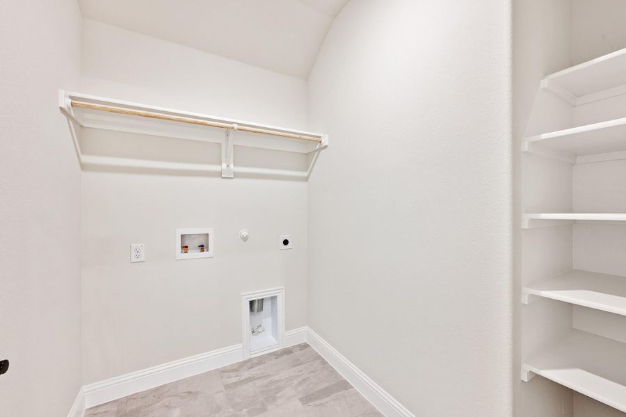 Laundry room with hanging rod, washer and dryer hookups, and built-in shelving on the right wall Laundry room with hanging rod, washer and dryer hookups, and built-in shelving on the right wall
