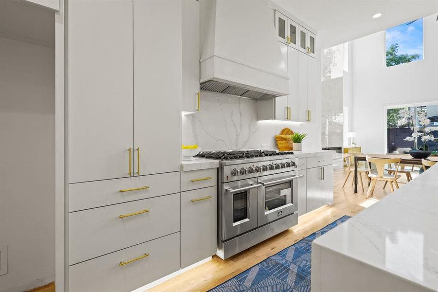 Kitchen with double oven range, premium range hood, light hardwood / wood-style floors, and tasteful backsplash