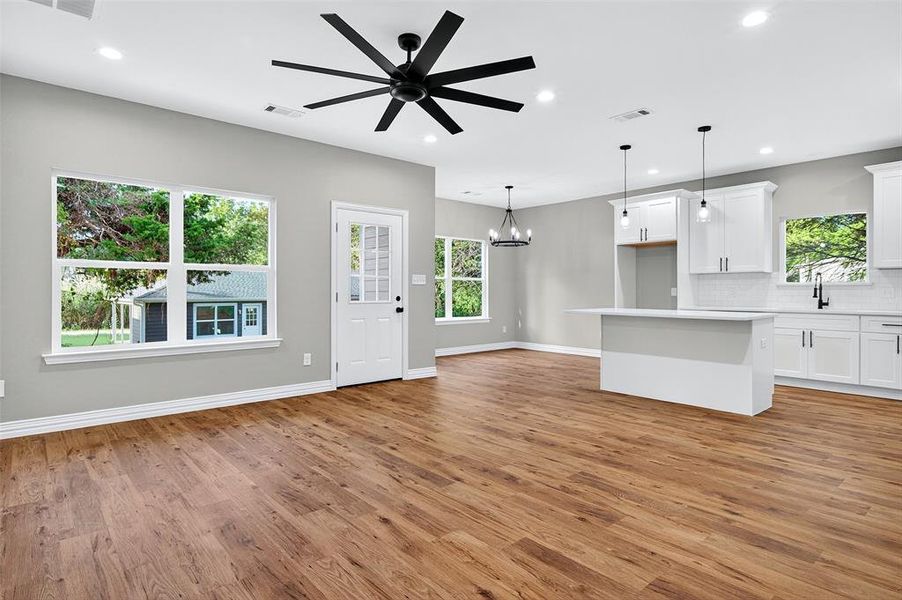 Unfurnished living room featuring a chandelier, recessed lighting, light wood-style flooring, and ceiling fan Unfurnished living room featuring a chandelier, recessed lighting, light wood-style flooring, and ceiling fan