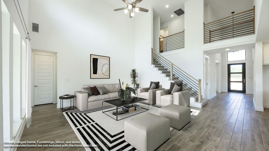 Living room with a high ceiling, wood finished floors, stairway, ceiling fan, and baseboards Living room with a high ceiling, wood finished floors, stairway, ceiling fan, and baseboards