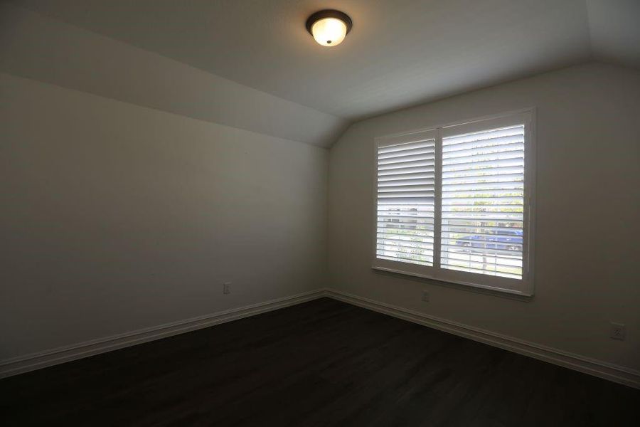 Room featuring dark wood-finish flooring, white baseboards, and neutral wall tones