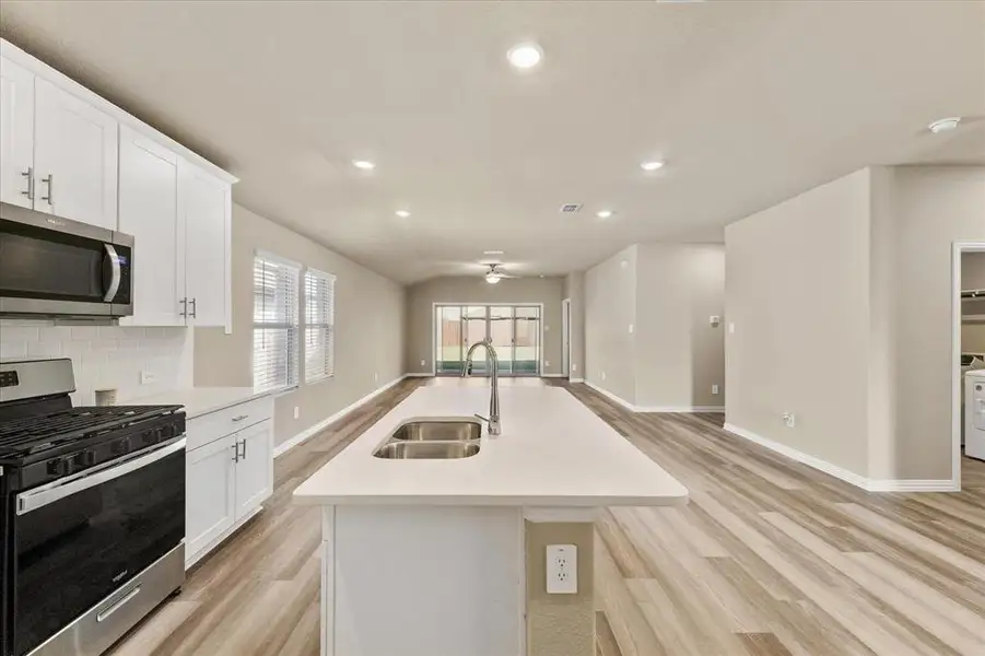Kitchen featuring appliances with stainless steel finishes, white cabinets, recessed lighting, light wood-type flooring, and open floor plan Kitchen featuring appliances with stainless steel finishes, white cabinets, recessed lighting, light wood-type flooring, and open floor plan