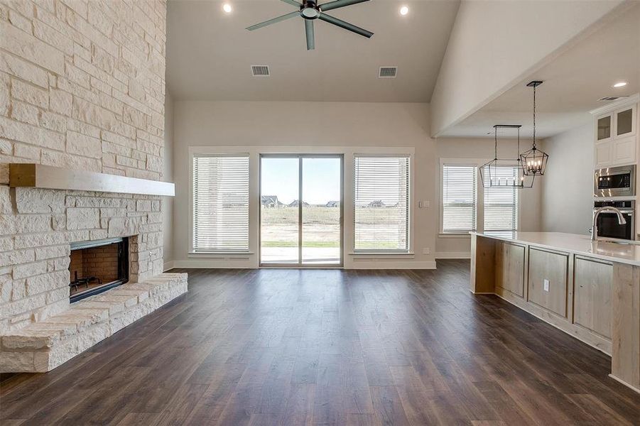 Unfurnished living room featuring a fireplace, ceiling fan, dark hardwood / wood-style flooring, and vaulted ceiling