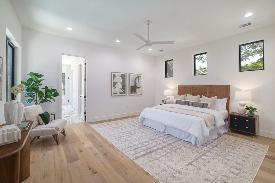 Spacious bedroom featuring light wood-finish flooring, recessed lighting, and a contemporary ceiling fan