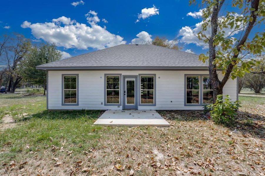 Back of house with roof with shingles, a patio, and a lawn Back of house with roof with shingles, a patio, and a lawn