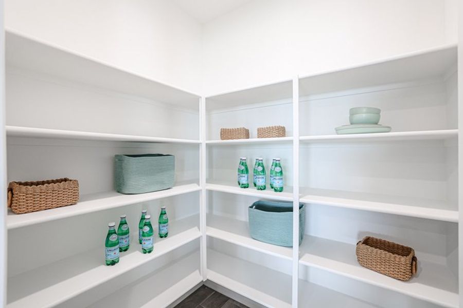 A white shelving unit with many bottles and baskets. A white shelving unit with many bottles and baskets.