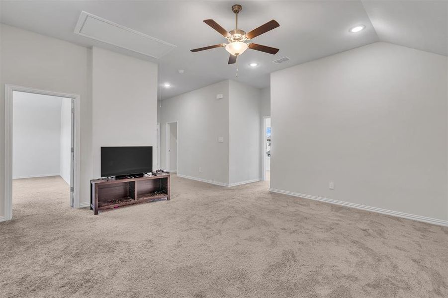 Living room with carpet floors, ceiling fan, and vaulted ceiling