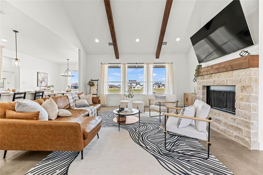 Living area featuring concrete flooring, a stone fireplace, a chandelier, and recessed lighting Living area featuring concrete flooring, a stone fireplace, a chandelier, and recessed lighting