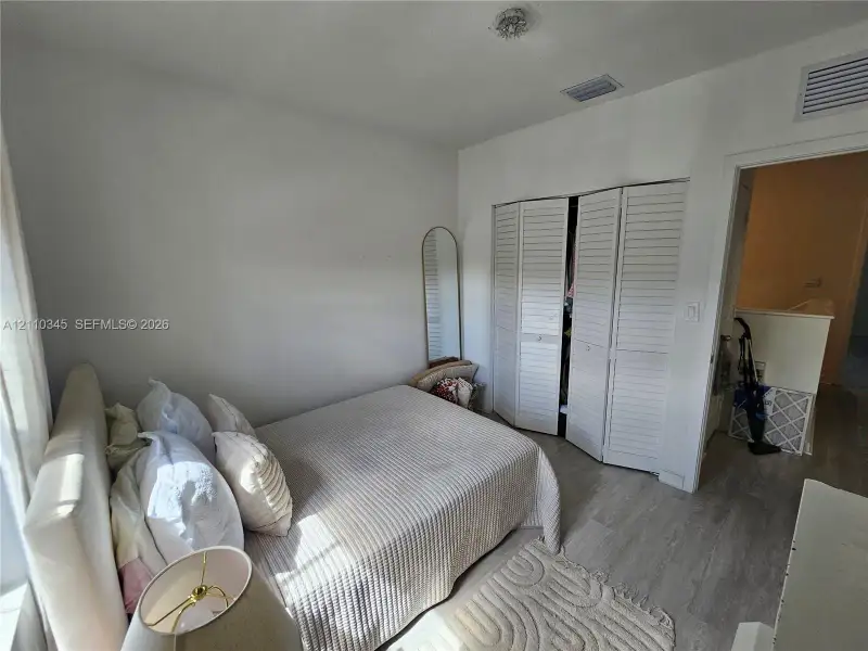 Bedroom featuring wood-finish flooring and a white, bi-fold louvered closet door