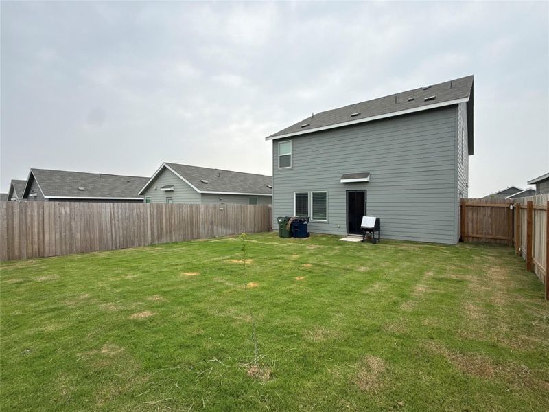 Expansive backyard featuring a green lawn and privacy fencing