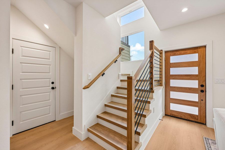 A well-lit entry features wood look flooring and a contemporary white oak solid wood tread staircase. A well-lit entry features wood look flooring and a contemporary white oak solid wood tread staircase.