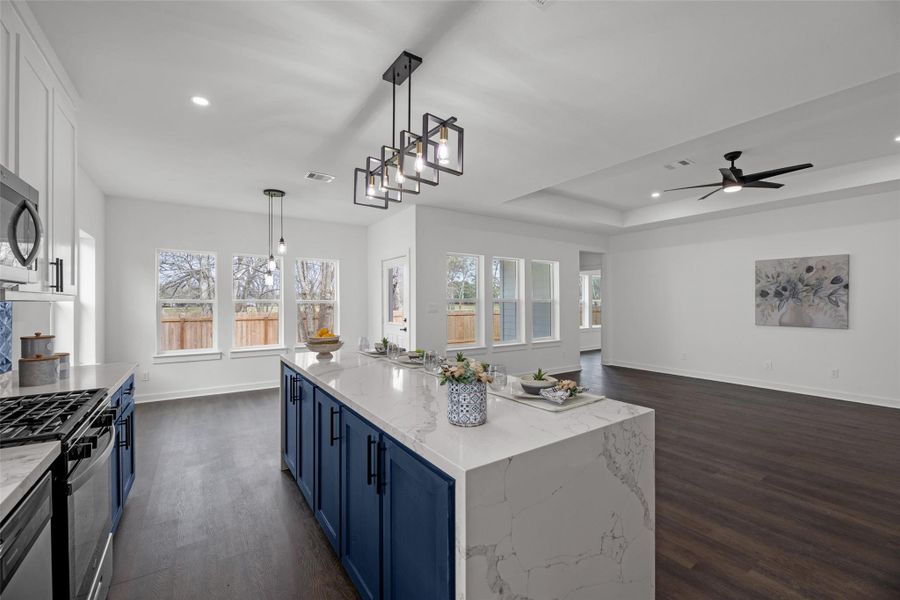 Showcases a modern open-concept kitchen and family area. The space is bright with natural light from multiple windows, and the family area includes a ceiling fan and sleek wood flooring, creating a welcoming atmosphere. Showcases a modern open-concept kitchen and family area. The space is bright with natural light from multiple windows, and the family area includes a ceiling fan and sleek wood flooring, creating a welcoming atmosphere.