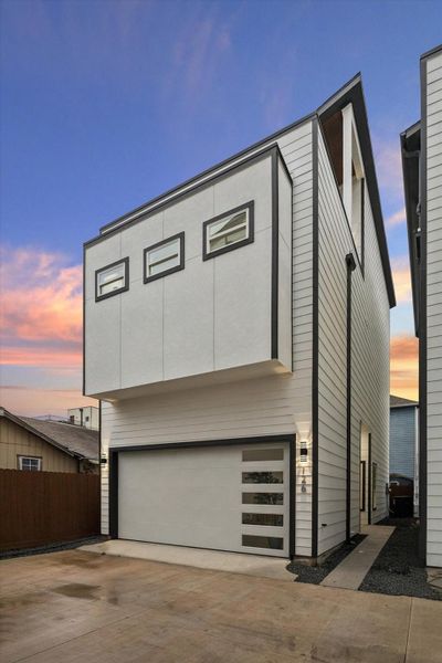 Modern three-story home with a sleek, angular design. Features a spacious garage with a contemporary door and small windows, accentuating clean lines. The exterior is clad in light siding with dark trim, offering a stylish, minimalist look. Ideal for urban living. Modern three-story home with a sleek, angular design. Features a spacious garage with a contemporary door and small windows, accentuating clean lines. The exterior is clad in light siding with dark trim, offering a stylish, minimalist look. Ideal for urban living.