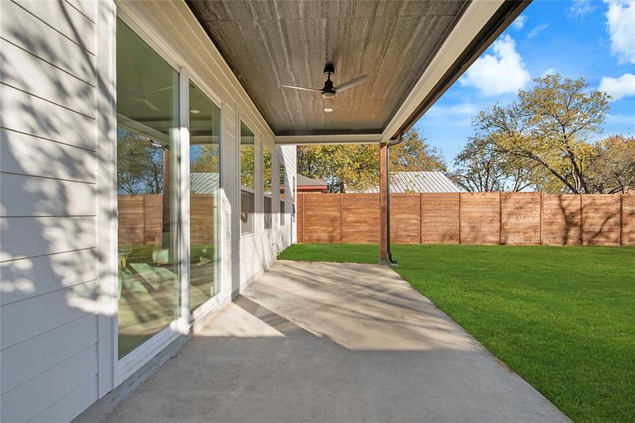 Fenced backyard featuring a ceiling fan and a patio Fenced backyard featuring a ceiling fan and a patio