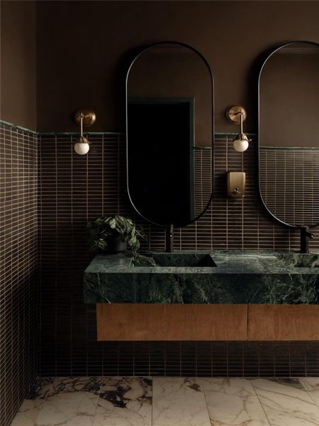 Rich marble vanity details pair with geometric wall tile in this moody bathroom design.