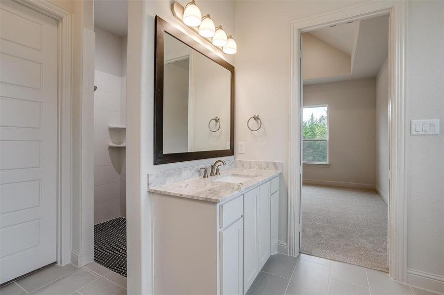 Bathroom with vanity, tile patterned flooring, and a tile shower