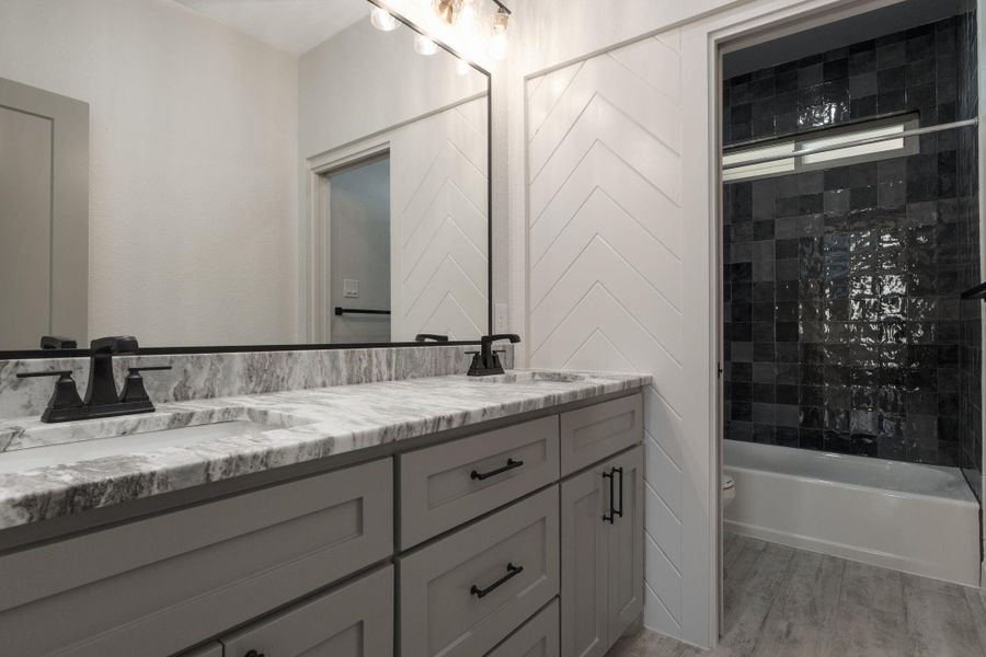Bathroom with double vanity, bathing tub / shower combination, and light wood-style floors