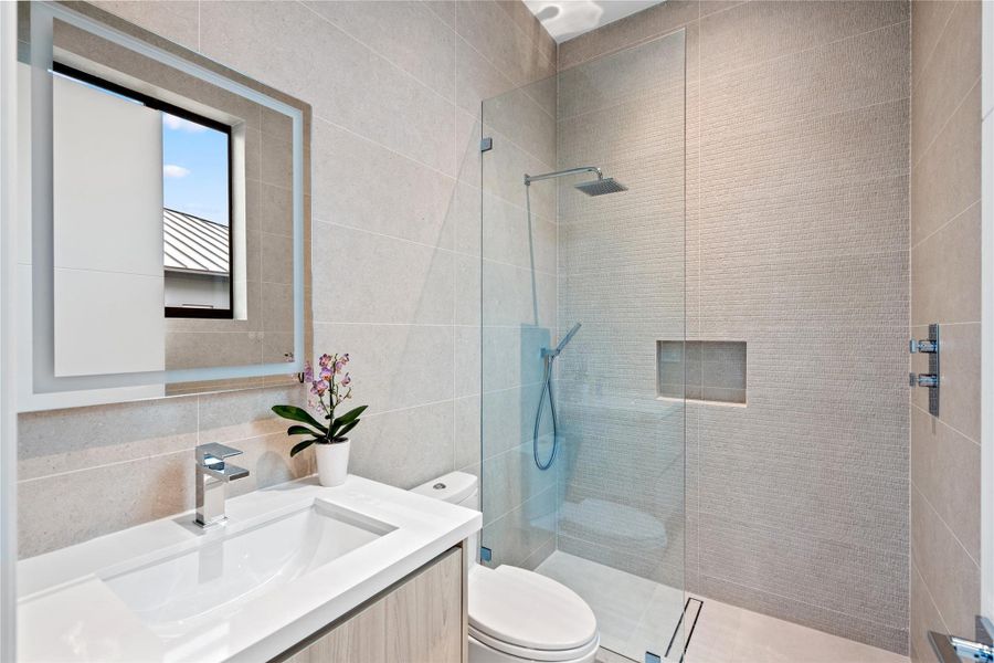 Sleek modern bathroom with glass-enclosed shower, vanity, and illuminated LED mirror. Sleek modern bathroom with glass-enclosed shower, vanity, and illuminated LED mirror.