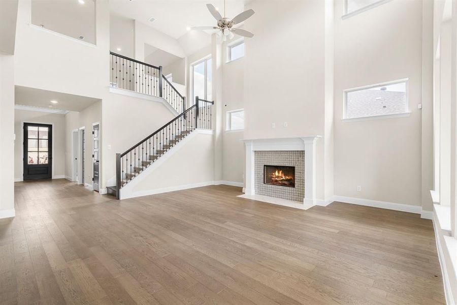 Unfurnished living room featuring a towering ceiling, crown molding, hardwood / wood-style floors, and ceiling fan