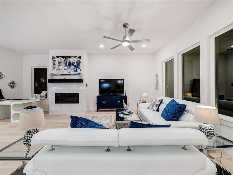 Living area featuring a premium fireplace, recessed lighting, light wood-type flooring, and ceiling fan Living area featuring a premium fireplace, recessed lighting, light wood-type flooring, and ceiling fan
