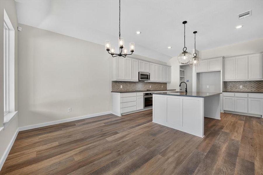 Open concept kitchen with a central island featuring a dark countertop and a matte black faucet Open concept kitchen with a central island featuring a dark countertop and a matte black faucet