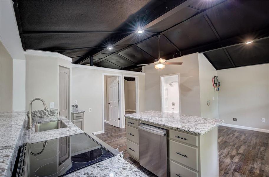 Kitchen featuring black stove, dark hardwood / wood-style flooring, sink, light stone countertops, and ceiling fan