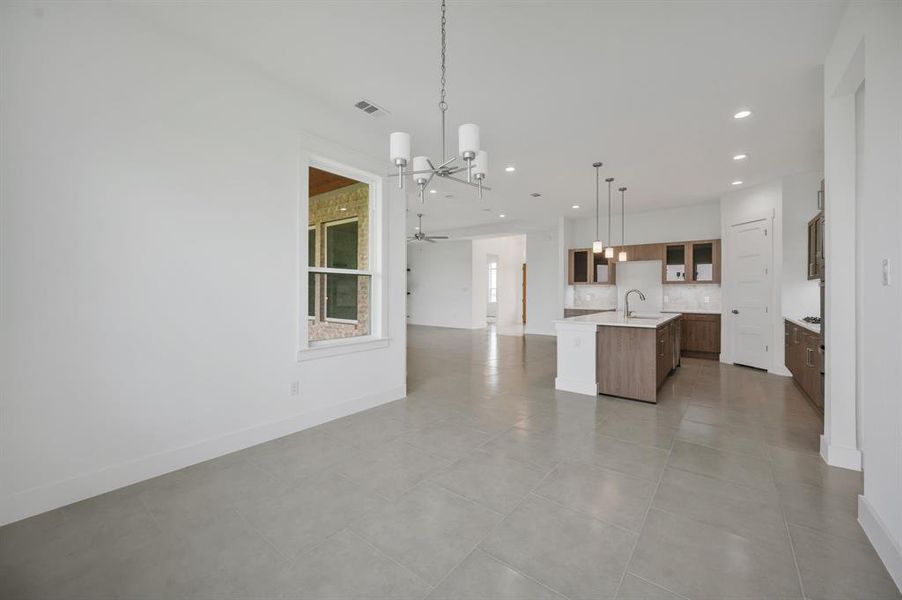 Kitchen featuring visible vents, open floor plan, an island with sink, light countertops, and tasteful backsplash Kitchen featuring visible vents, open floor plan, an island with sink, light countertops, and tasteful backsplash