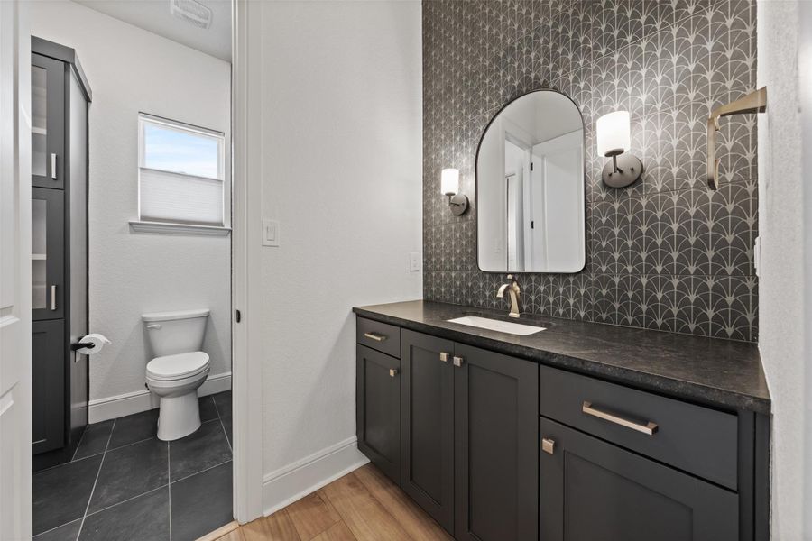 Bathroom featuring baseboards, backsplash, vanity, and toilet