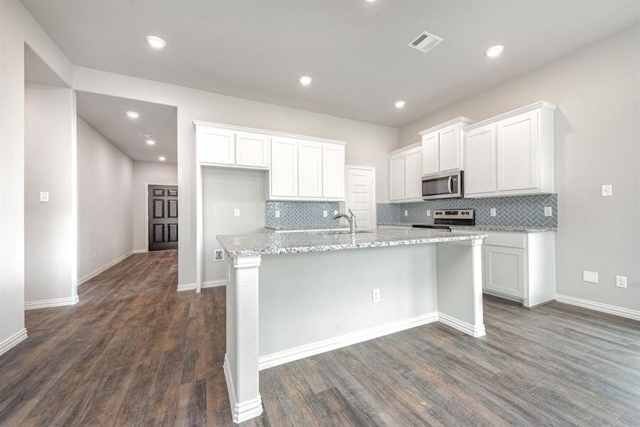 Kitchen featuring a kitchen island with sink, dark hardwood / wood-style floors, tasteful backsplash, white cabinetry, and stainless steel appliances