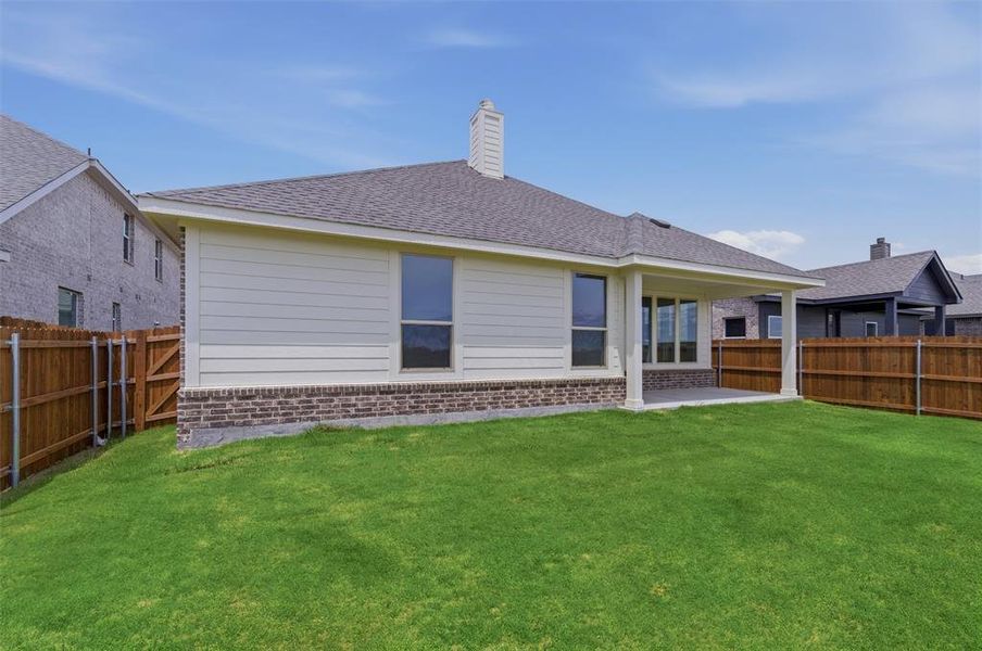 Spacious backyard featuring a manicured lawn, full privacy fencing, and a covered concrete patio