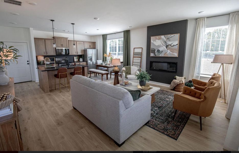 Living room featuring light wood-type flooring, a glass covered fireplace, and recessed lighting