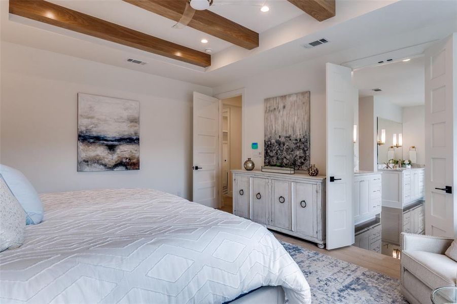 Bedroom featuring ensuite bathroom, beam ceiling, visible vents, and wood finished floors Bedroom featuring ensuite bathroom, beam ceiling, visible vents, and wood finished floors