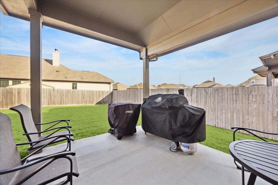 View of extended covered patio and fenced backyard