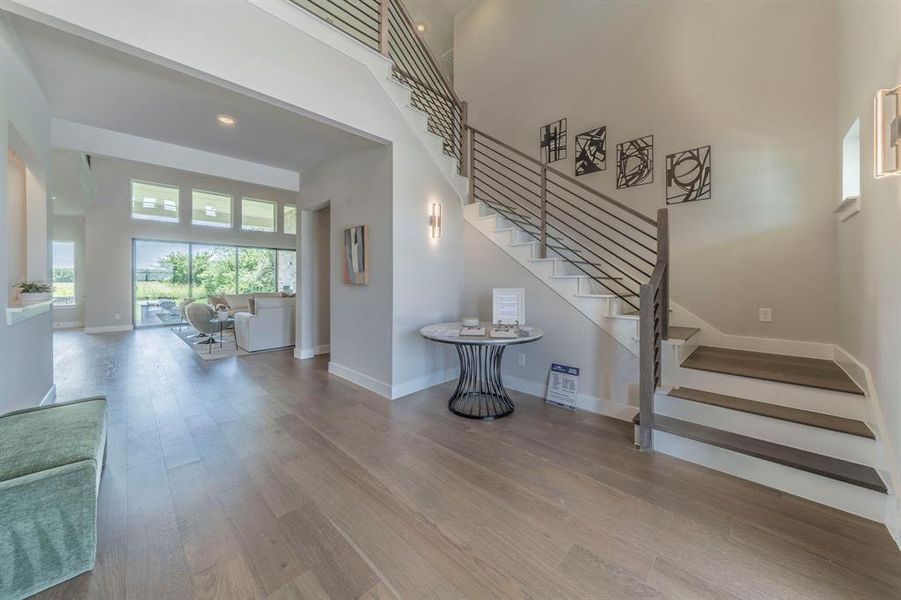 Stairway featuring wood finished floors, a high ceiling, and recessed lighting Stairway featuring wood finished floors, a high ceiling, and recessed lighting