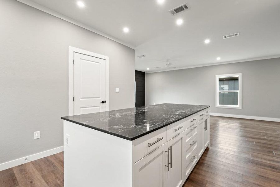 Kitchen with white cabinetry, recessed lighting, dark wood finished floors, a center island, and dark stone counters