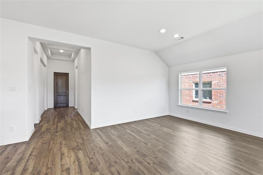 Spacious room featuring wood-finish flooring, recessed lighting, and a prominent window with white trim