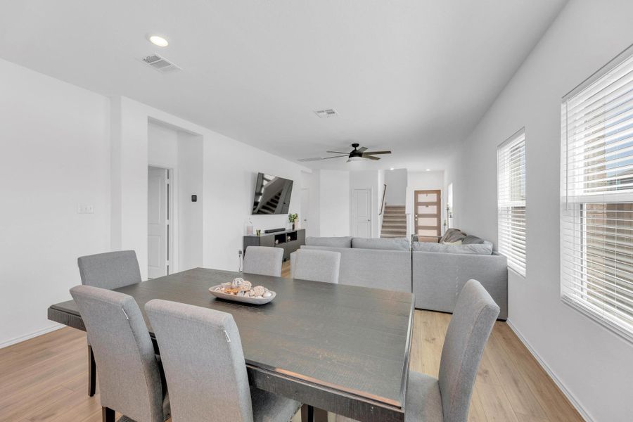 Dining area featuring visible vents, light wood-style flooring, a ceiling fan, and stairs