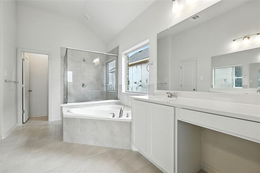 Bathroom with a shower stall, a bath, vanity, light tile patterned floors, and vaulted ceiling