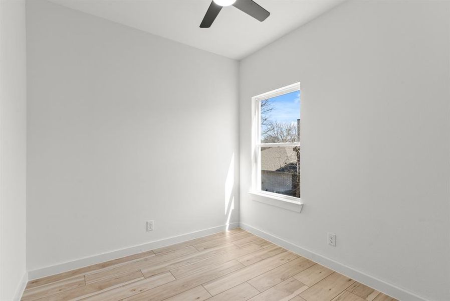 Secondary bedroom featuring baseboards, a ceiling fan, and light wood-style floors