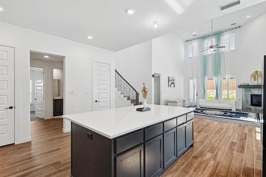 Kitchen with ceiling fan, a center island, dark hardwood / wood-style flooring, pendant lighting, and a fireplace