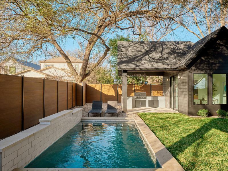 View of swimming pool with a fenced backyard, exterior kitchen, and patio surround