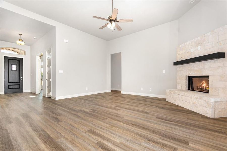 Unfurnished living room with wood finished floors, a fireplace, and ceiling fan