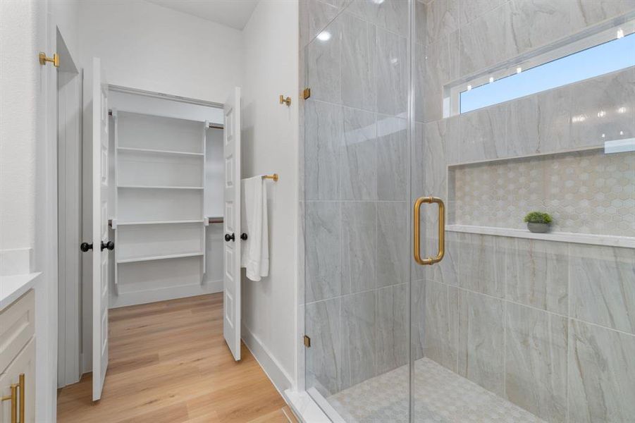 Bathroom featuring vanity, a spacious closet, a stall shower, and light wood finished floors