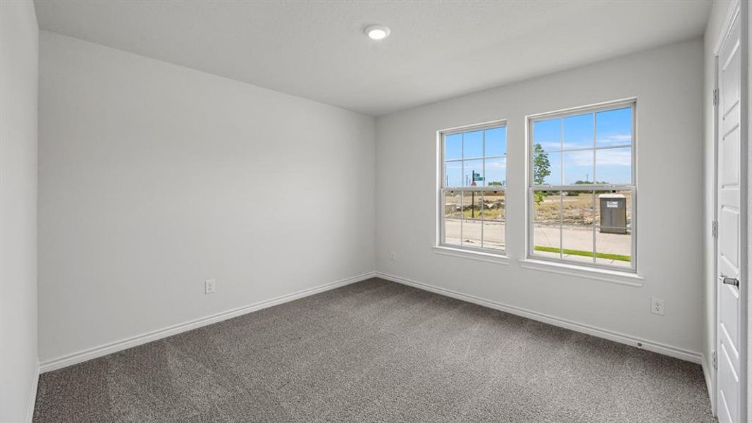 Neutral-toned room featuring a single recessed ceiling light fixture, plush gray carpeting, white baseboards, and two large window panes with white grids Neutral-toned room featuring a single recessed ceiling light fixture, plush gray carpeting, white baseboards, and two large window panes with white grids